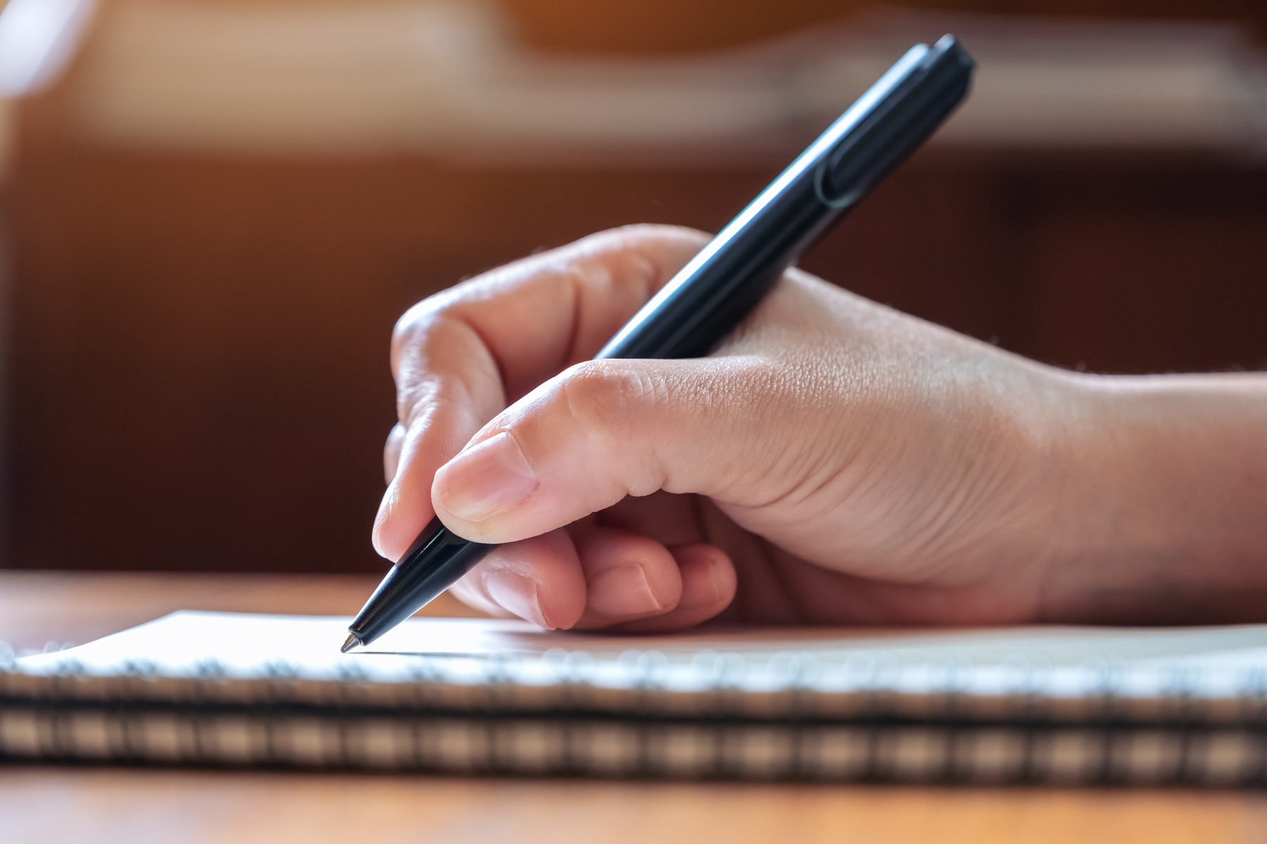 a hand holding a pen to journal