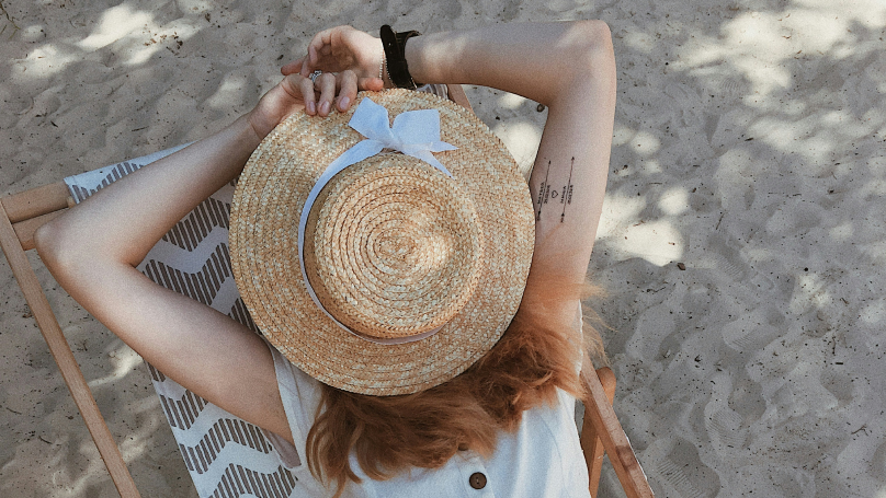 An image of a woman in white top lying on the chair.