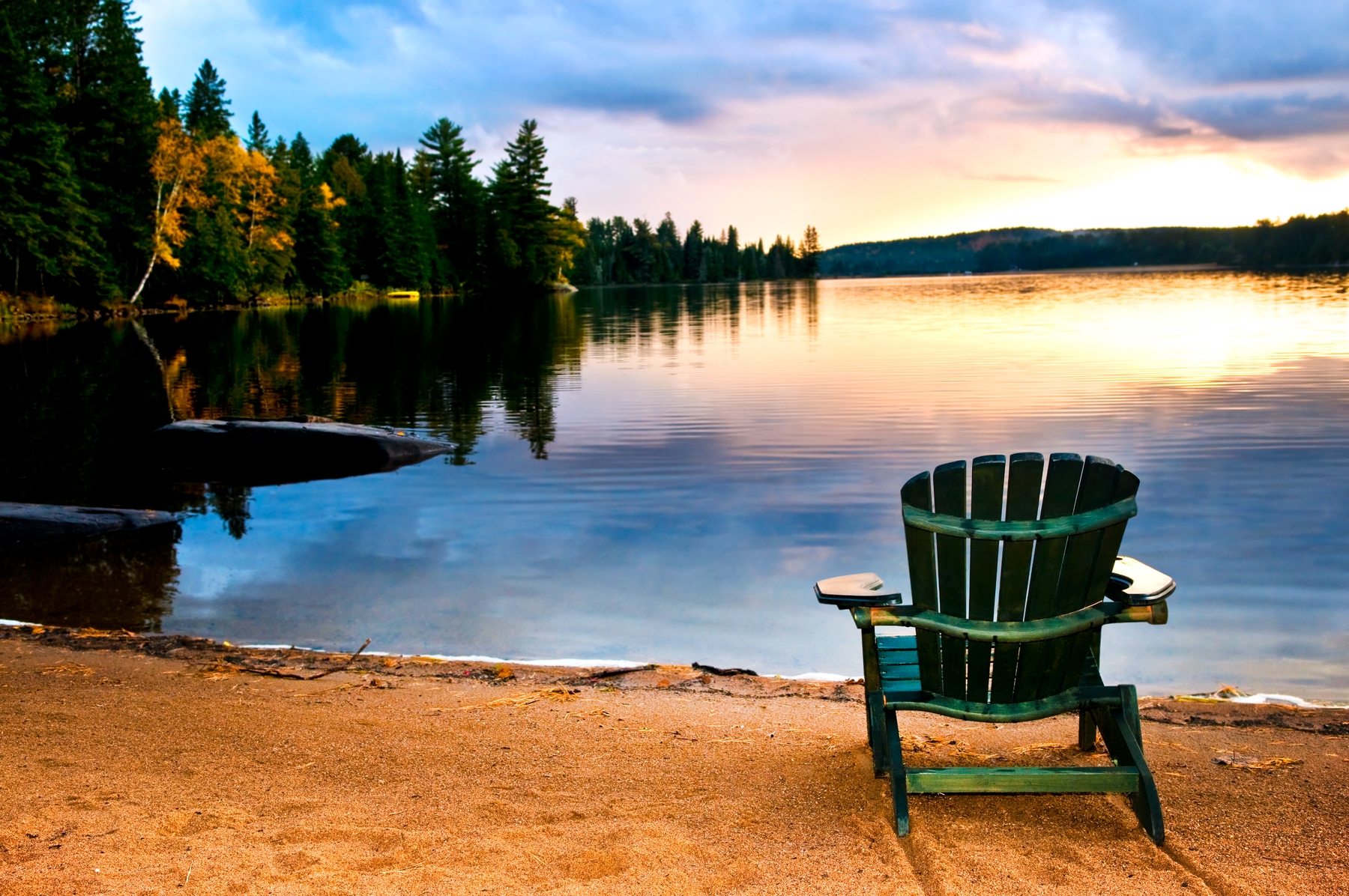 Muskoka chair by the lake at sunset