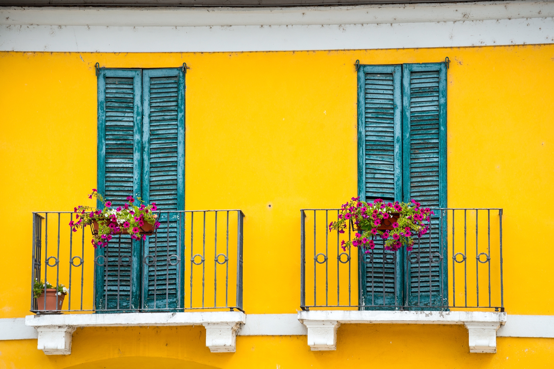 house front with yellow walls and turquoise window sills and balcony in Milan