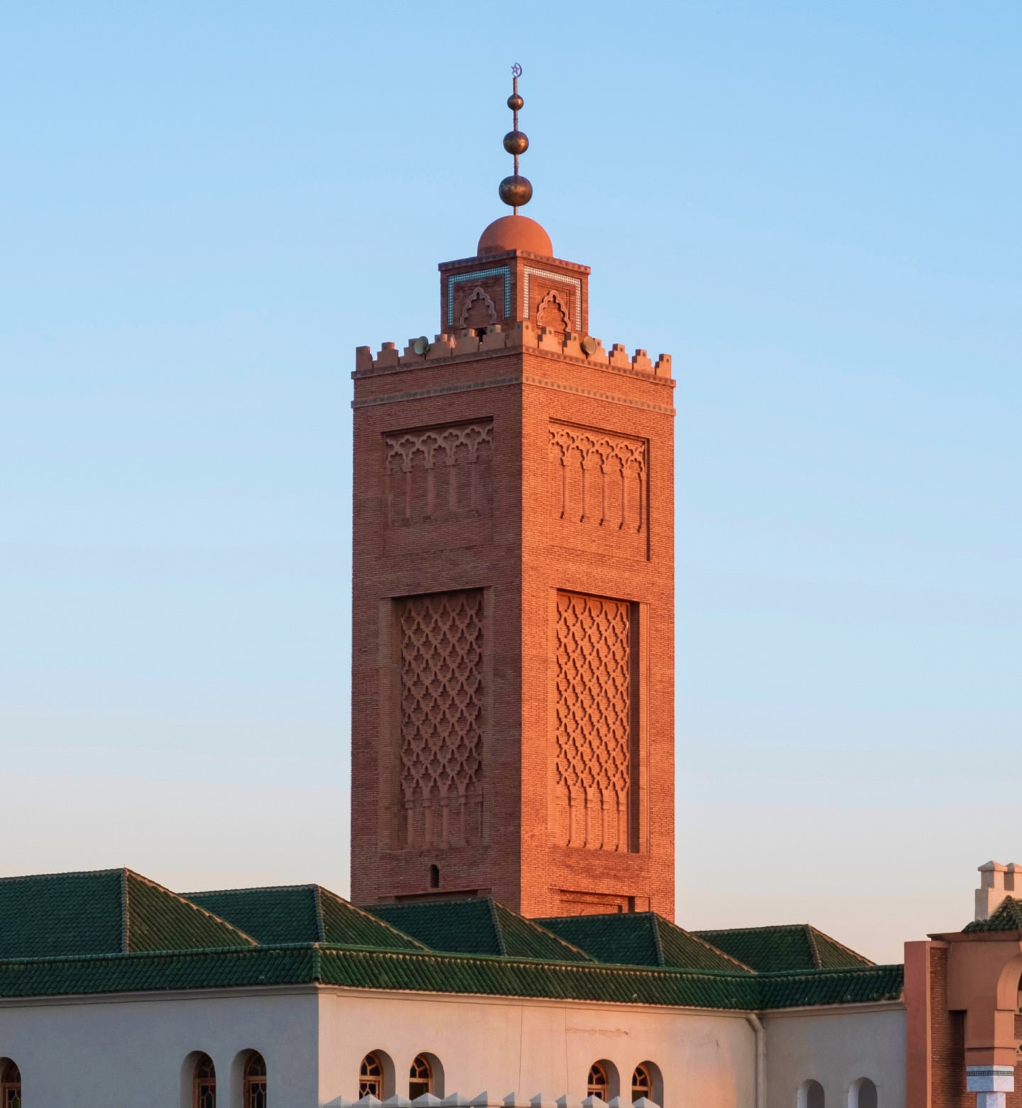 Le minaret d'une mosquée en briques rouges à Oujda, au Maroc, brille sous le soleil du soir.