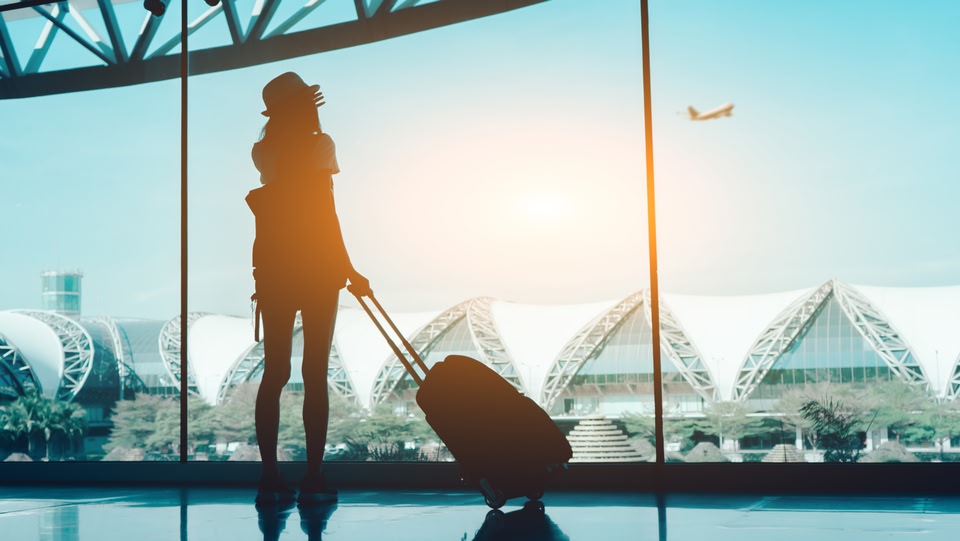 Frau schaut auf ein startendes Flugzeug