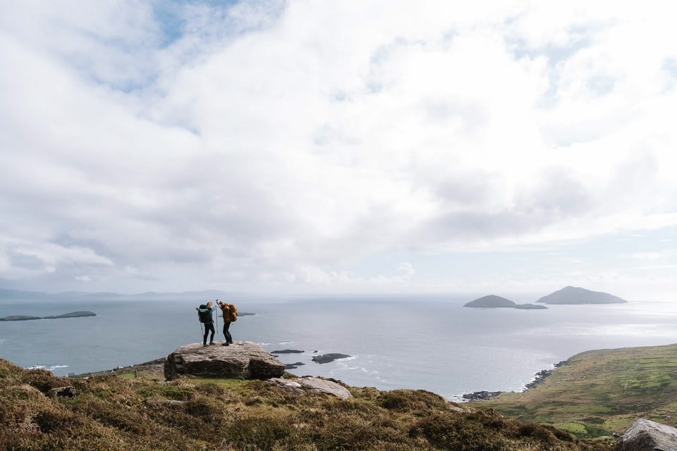 Hikers celebrating on top of rock overlooking the sea along Kerry Way 