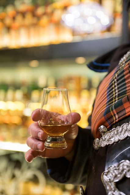 Piper stands with a glass of whisky at Scotch Whisky Experience