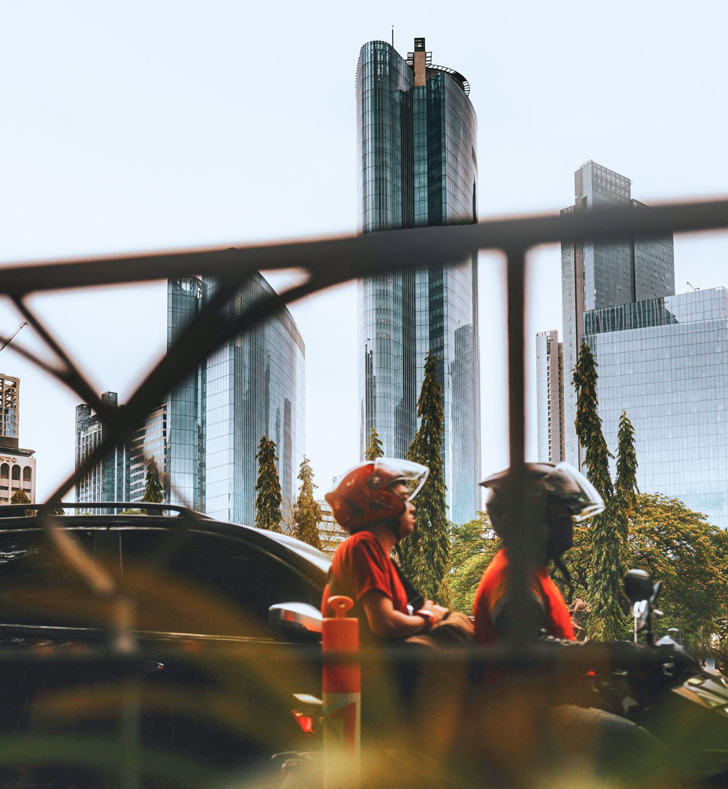 Two people on a scooter ride past modern skyscrapers in Manila, Philippines.