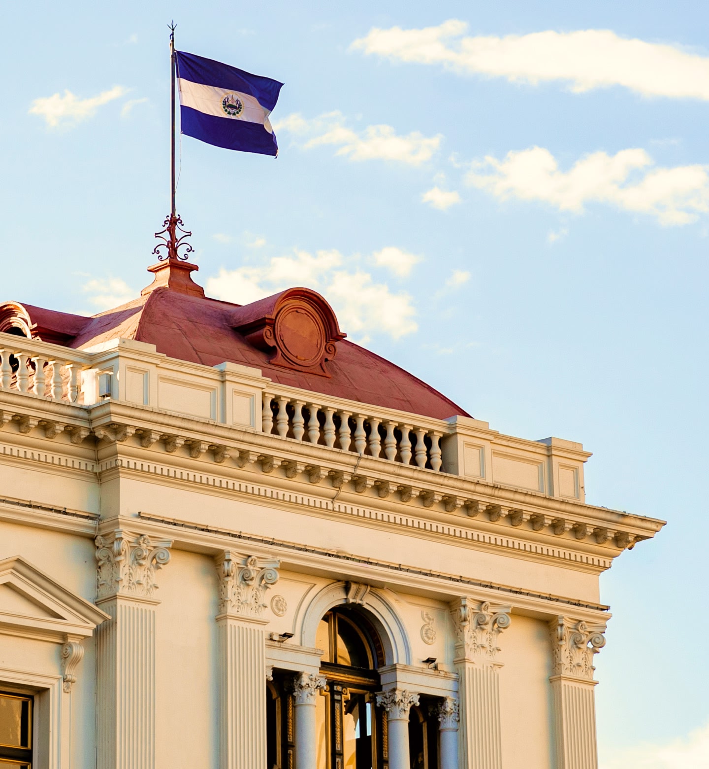 The El Salvador flag flying above an ornate neoclassical rooftop in the capital San Salvador.