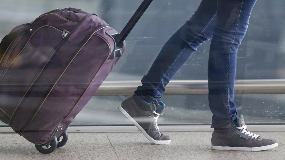Person schleppt einen Koffer vor einen Flughafen