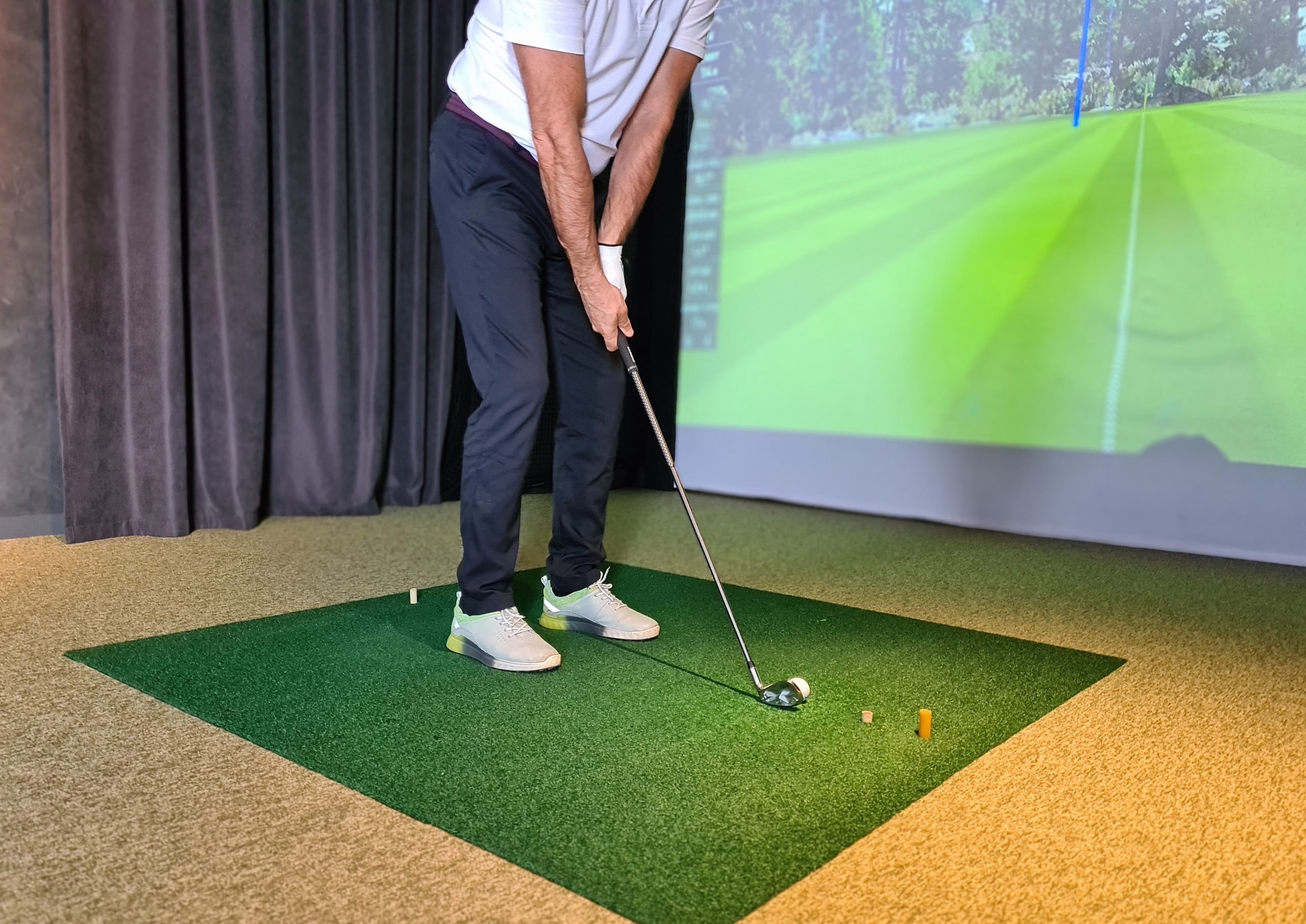 Person playing golf indoors on a golf simulator.