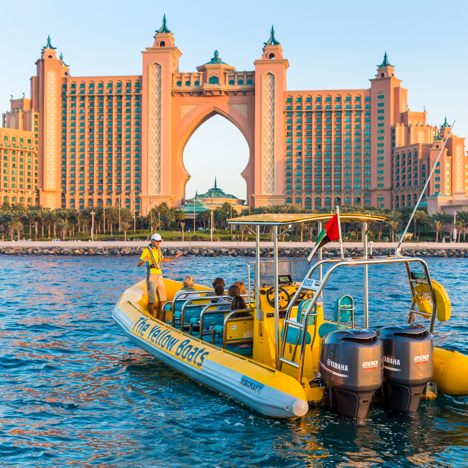 The Yellow boats tour, Yellow Boat tour guide and tourists in the boat with the Dubai Marina in the background during the day.