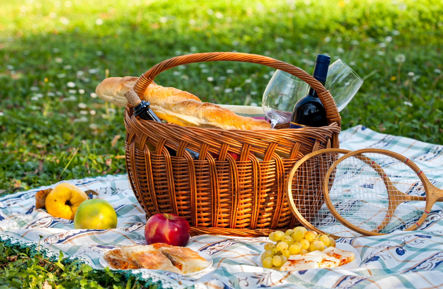 a picnic basket with baguette and wine in a park