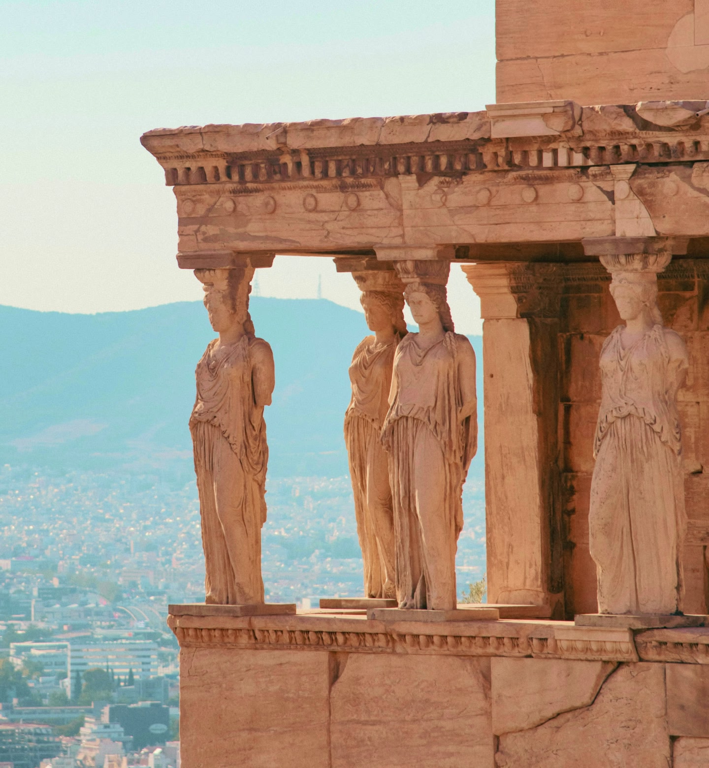 Oude kariatiden op het Erechtheion met uitzicht op Athene bij zonsondergang.