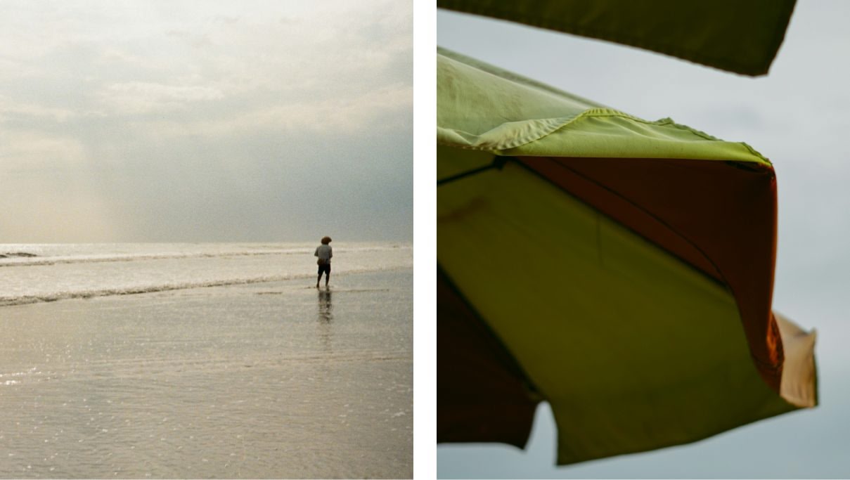 A person standing at the beach near the seashore and the underside of a beach umbrella