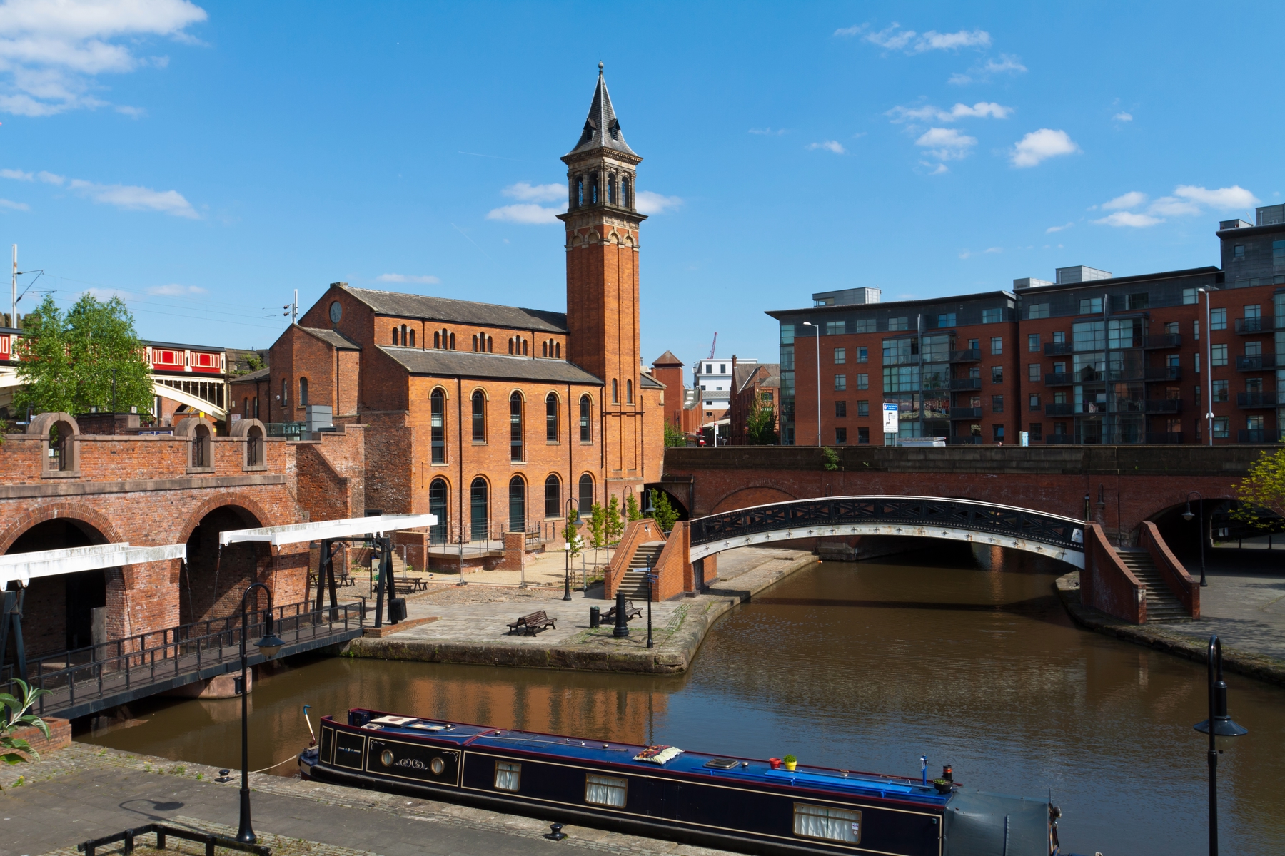 Picture shows the city of Manchester and a canal boat on its canal.