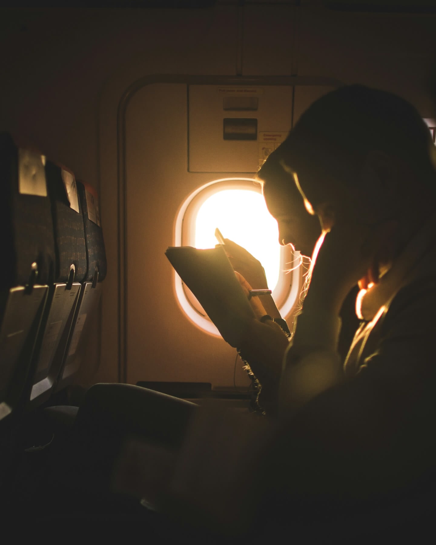 Dos personas leyendo en un avión a contraluz por la luz que entra por la ventanilla