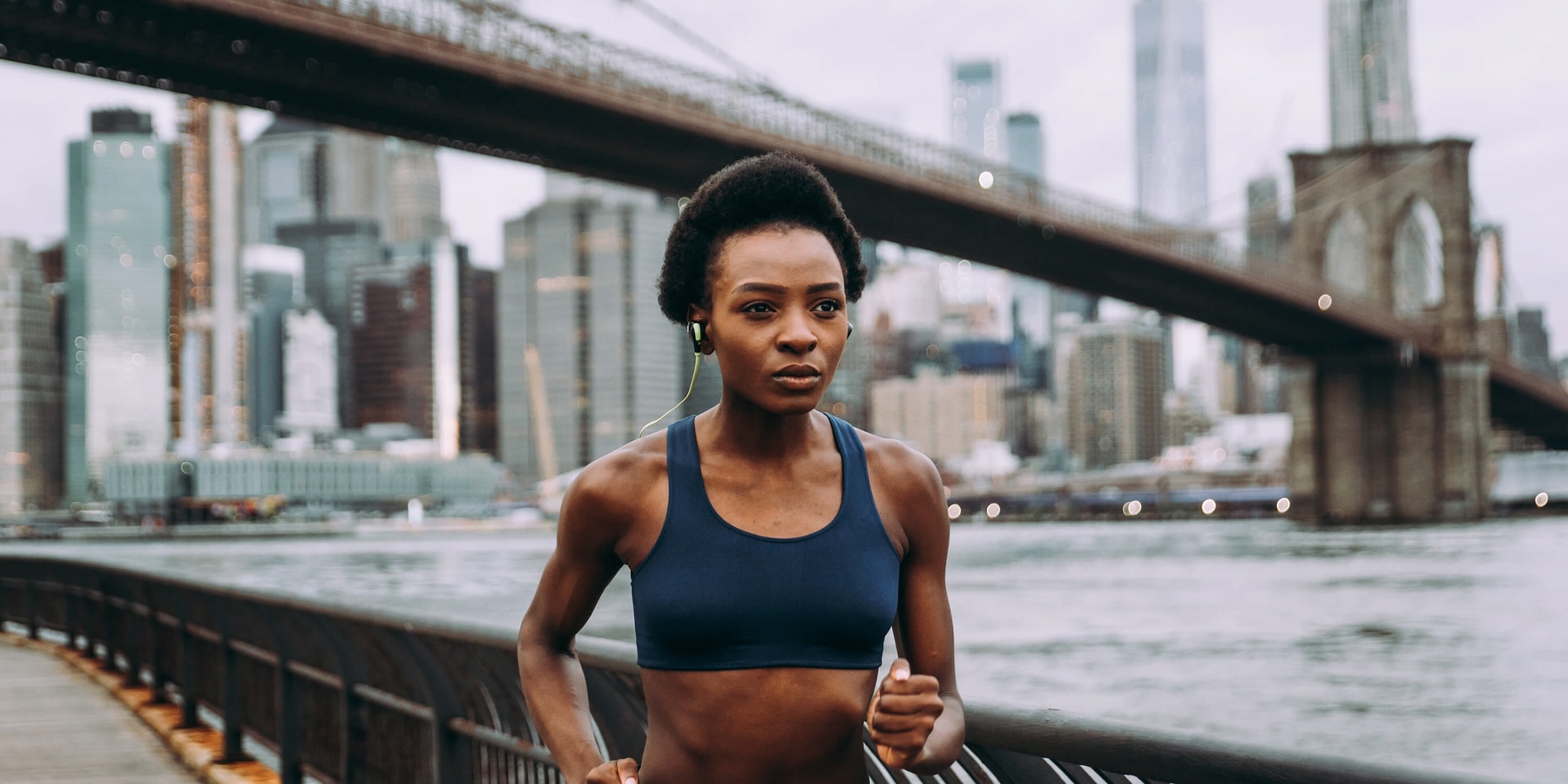 Person running next to a river with New York skyline behind them