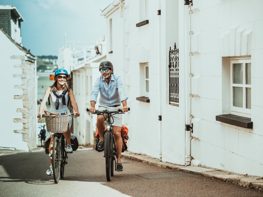 Couple cycling through a quaint village in Jersey