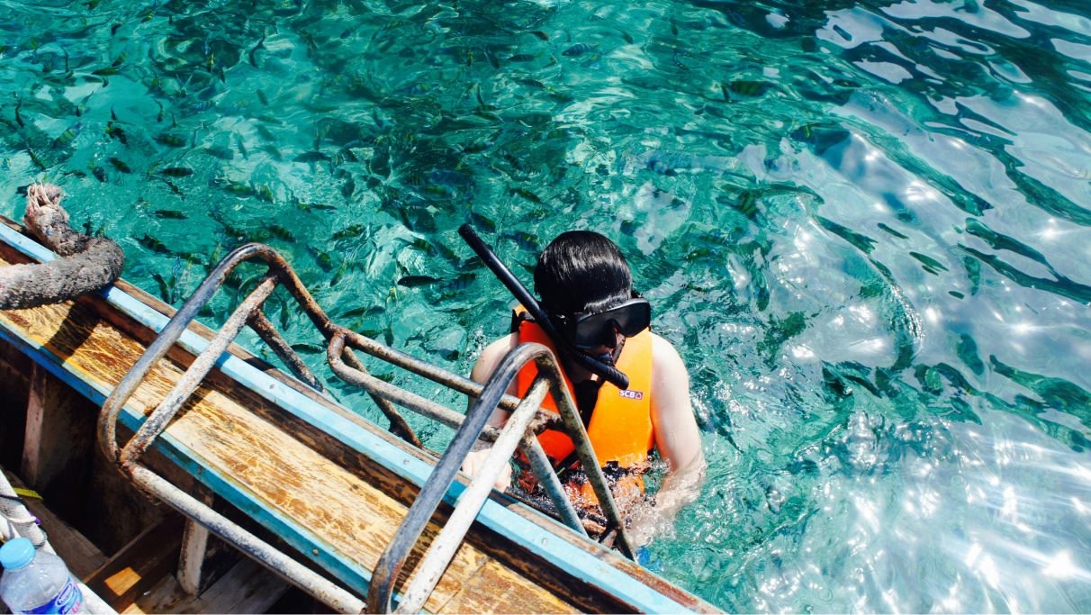 Um mergulhador subindo em um barco em um lindo oceano azul cheio de peixes