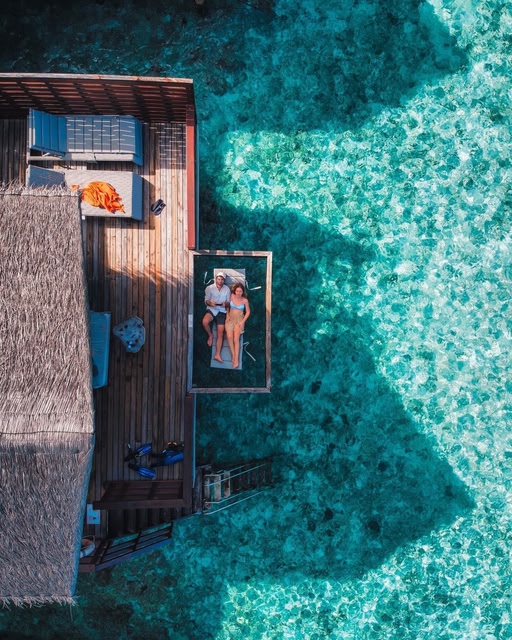 Couple lounging over clear waters in Maldives
