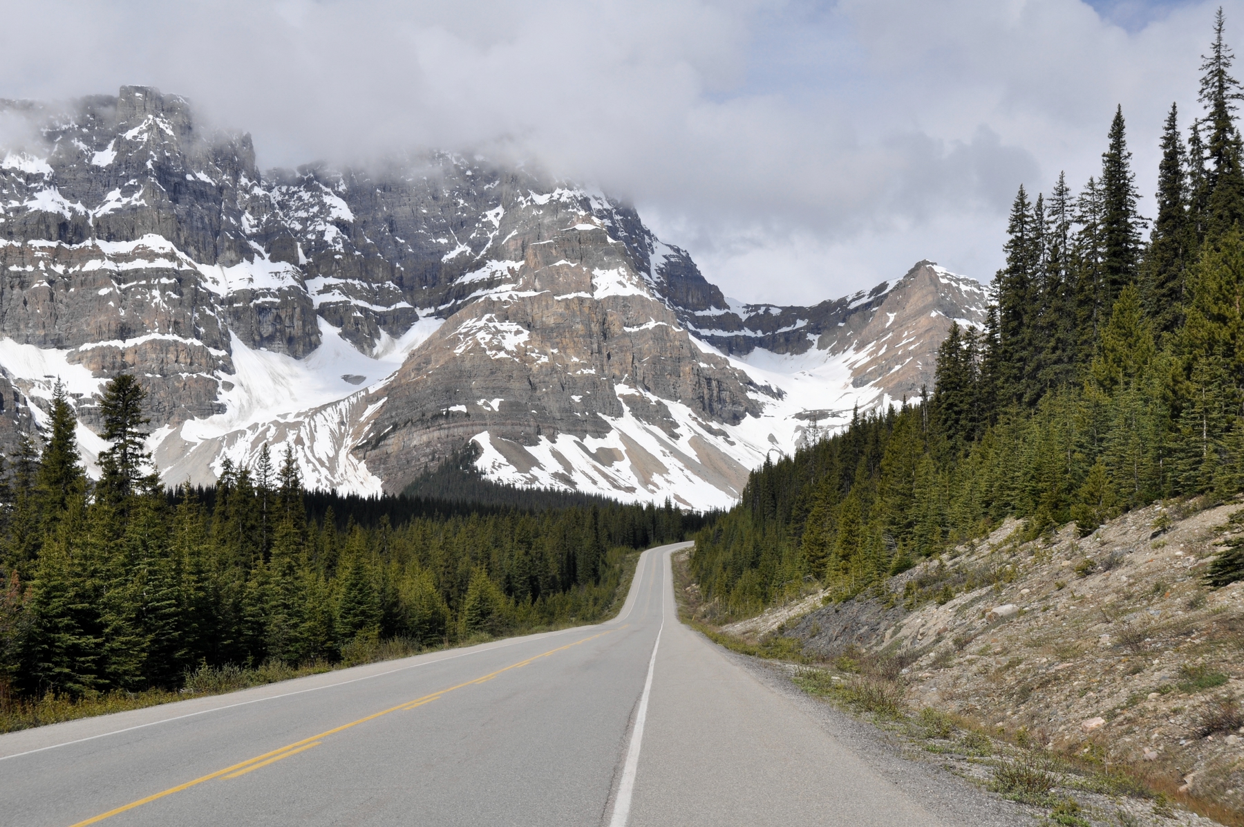 highway in the snowy Rocky Mountains. driving is the most budget friendly option for a longer trip to the Canadian Rockies