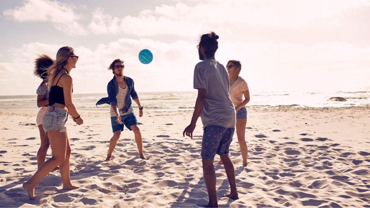 Group of people playing volleyball at the beach during daytime.