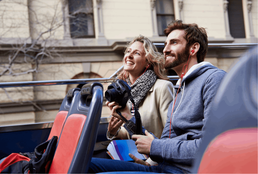 A joyful man and woman seated side by side, enjoying a ride on an open-top tour bus. Smiles and excitement abound as they take in the sights of Seoul.