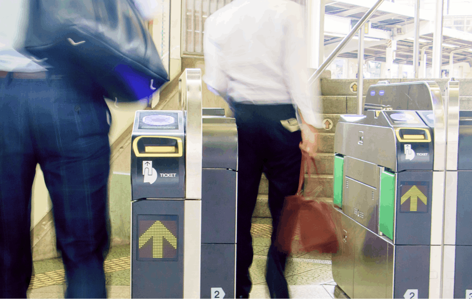 A picture of some business people entering a turnstyle on one of many of Tokyo's public transit systems.