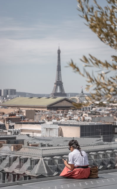 traveller sitting on a rooftop the Eiffel Tower in the distance.