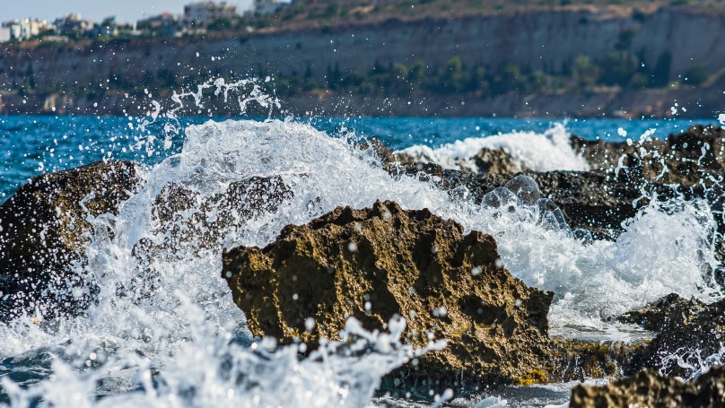 Golven die tussen de rotsen in de zee breken.