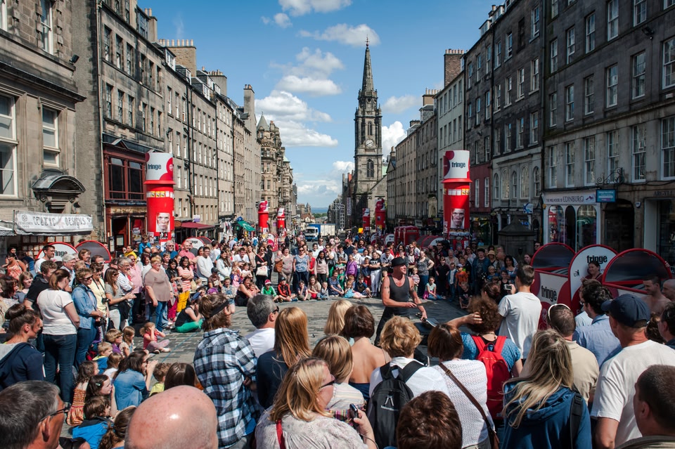 A street performer with a large crowd gathered in Edinburgh during the Fringe festival.