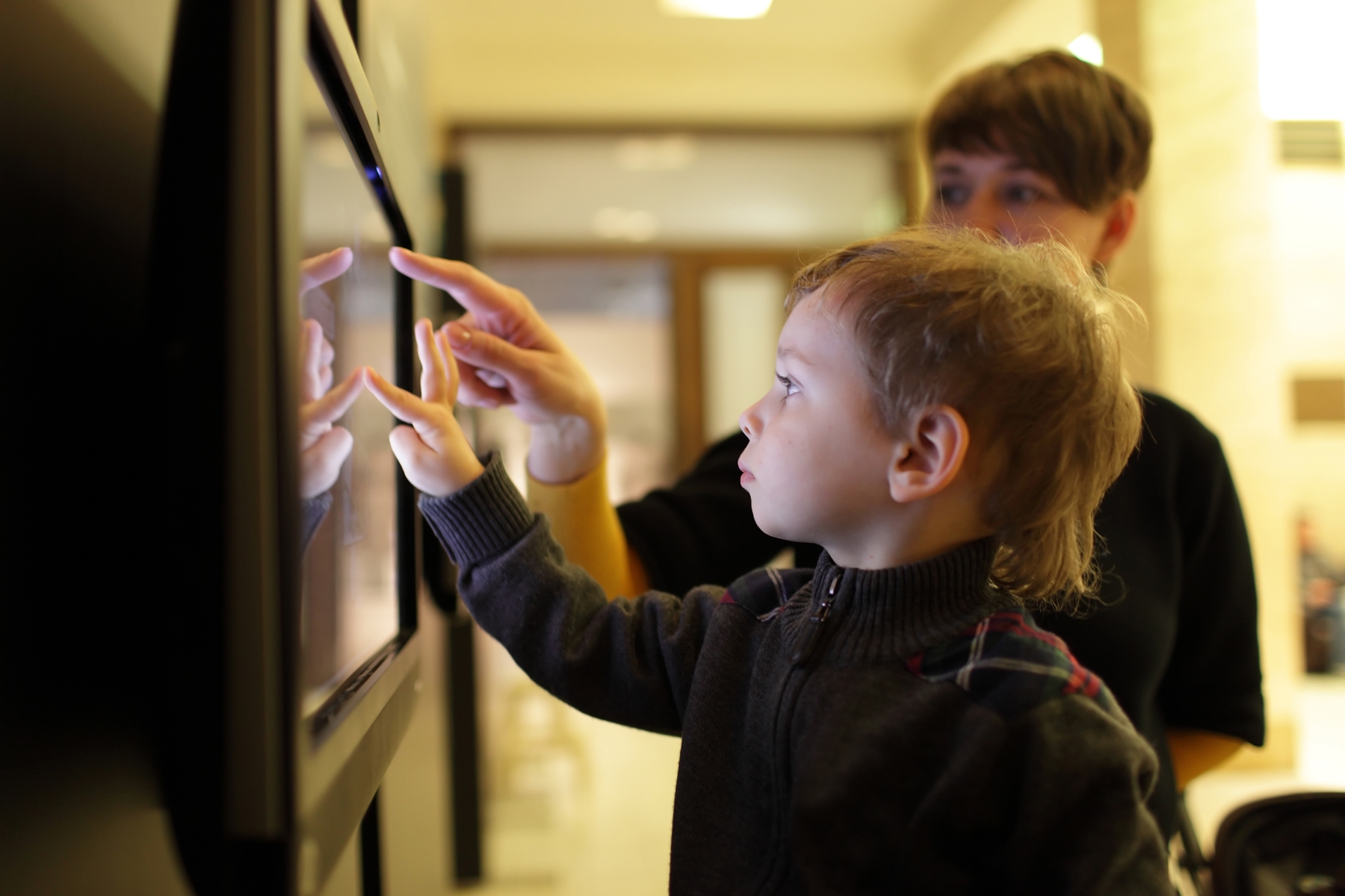 Two young boys tapping on a screen in a museum