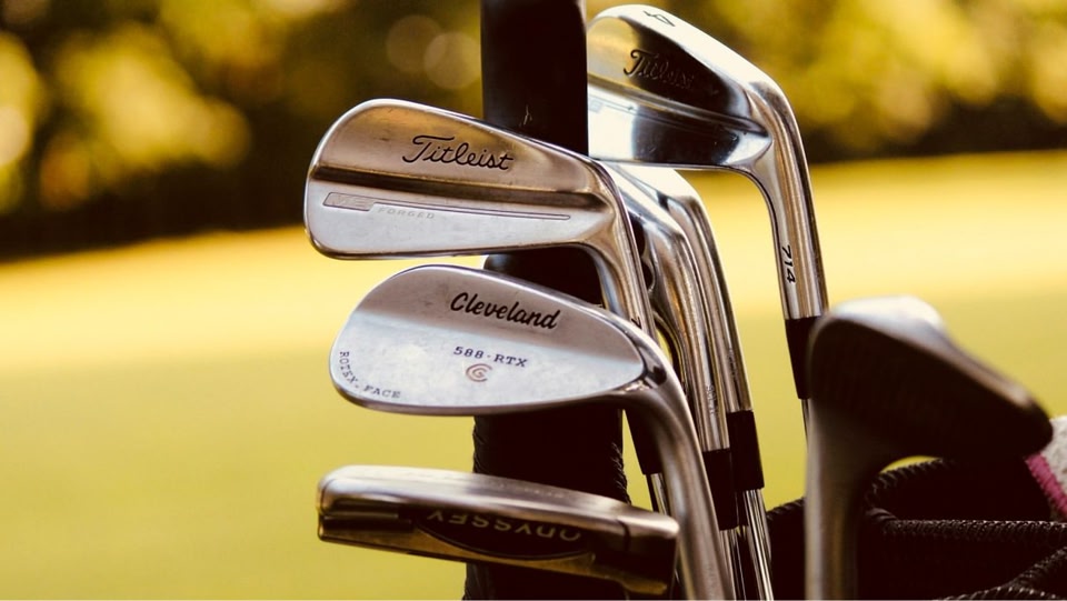Palos de golf de Titleist, Cleveland y Odyssey en una bolsa de golf.