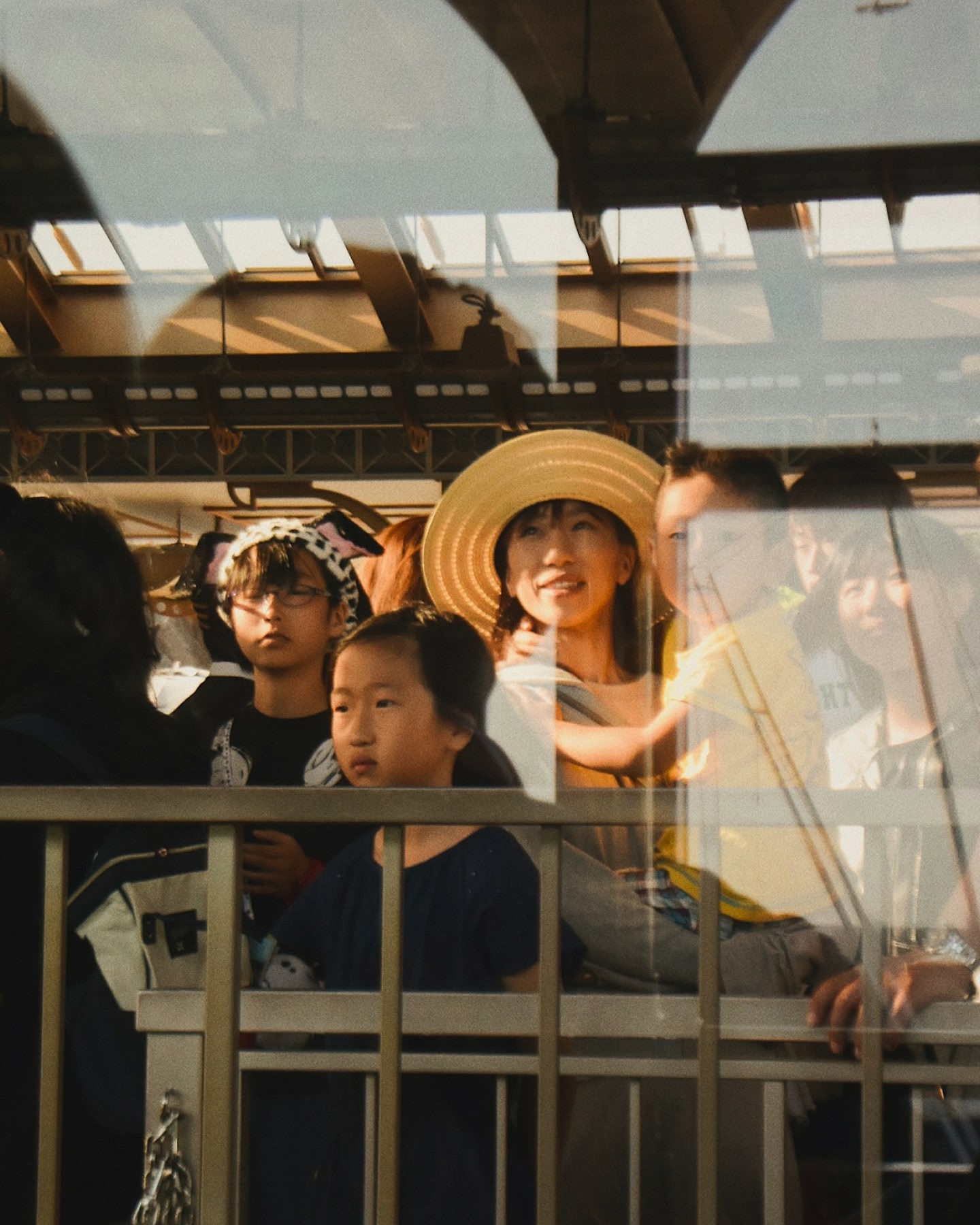 麦わら帽子をかぶった女性が、賑やかな駅で家族と一緒に微笑んでいる。