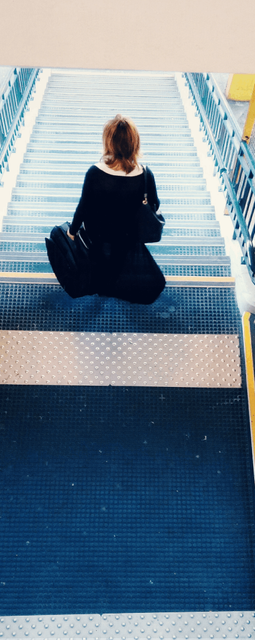 A woman walking down a flight of stairs  with her bags at the airport after arriving at Da Nang