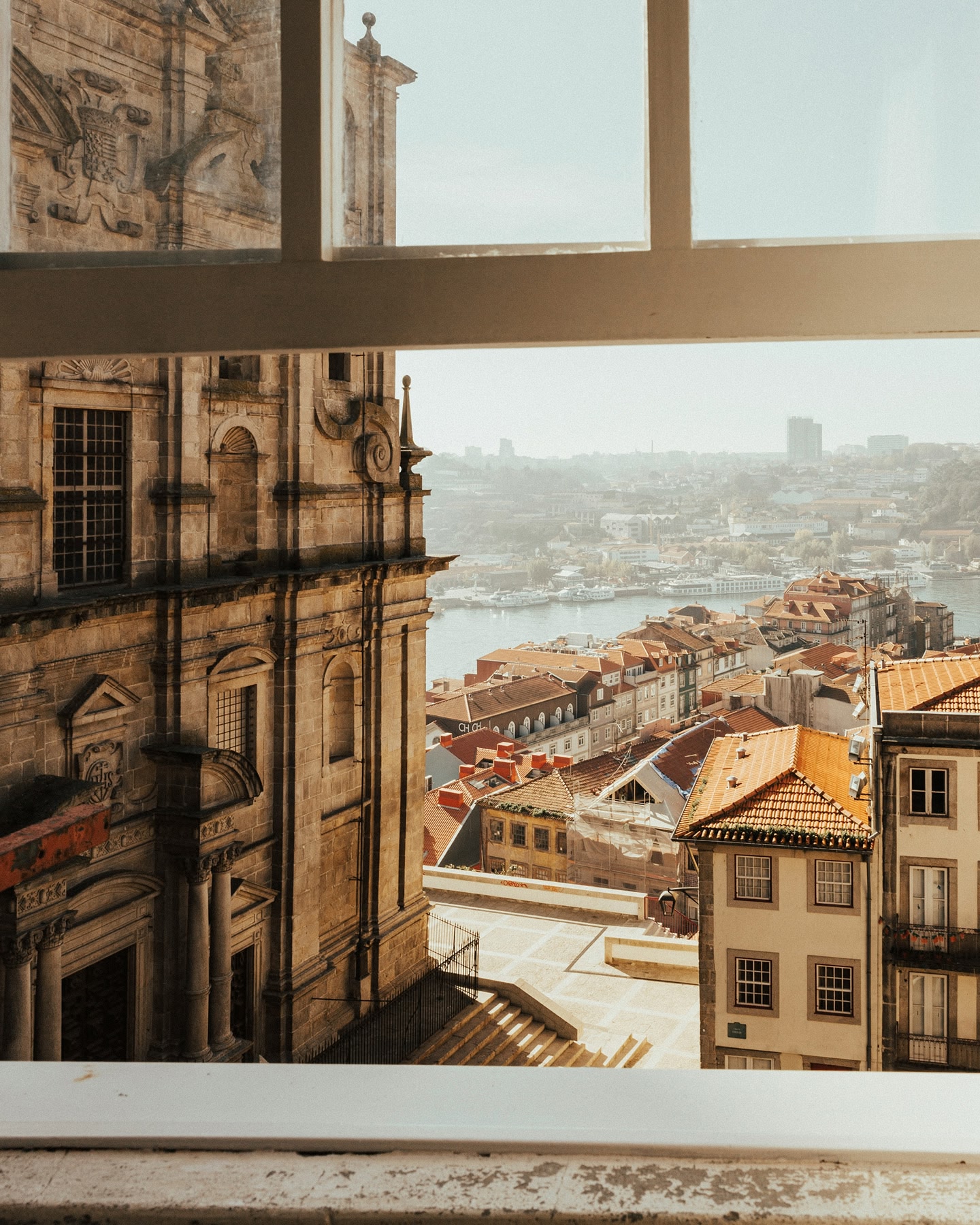 Une vue sur les toits de la ville et sur le fleuve encadrés par une fenêtre à Porto, au Portugal.