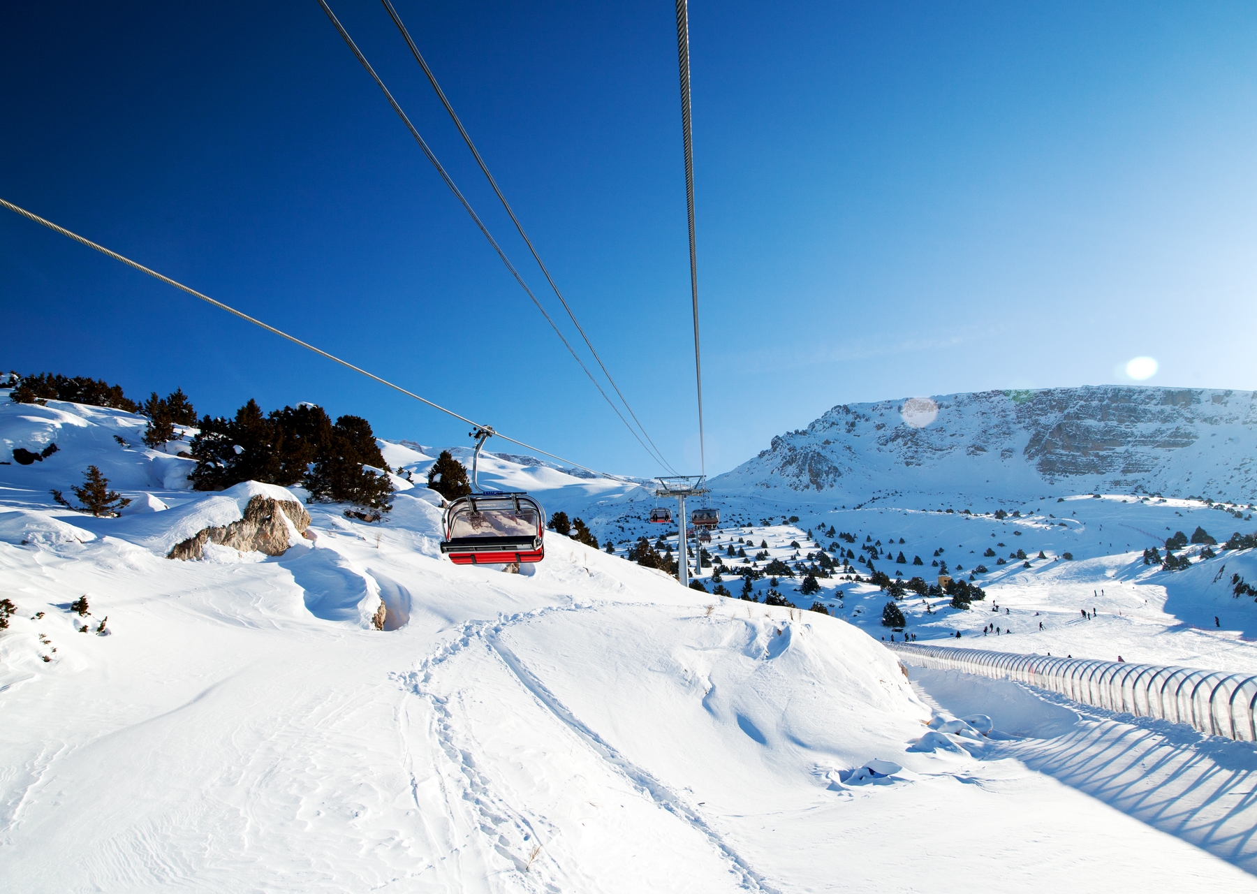 Cable cars making their way above a snowy mountain towards the camera
