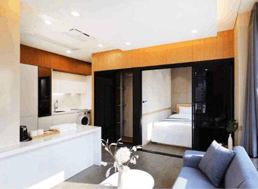 Inside a Myeong-dong hotel room, glimpse a small kitchen, a comfortable blue sofa, and an inviting double bed, creating a cozy and functional room.