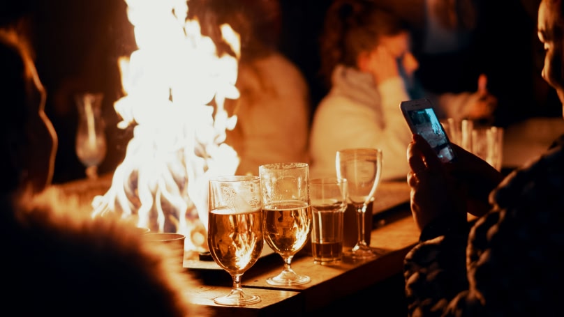 Una persona sta fotografando delle bevande davanti a un fuoco in un mercatino di Natale.