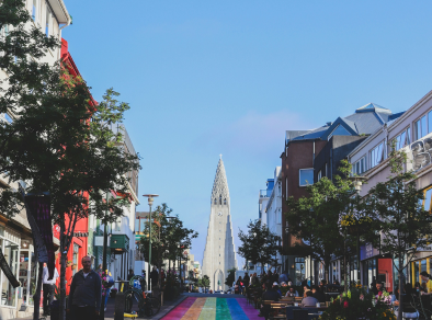An image of people walking on a street close a white building during day time.