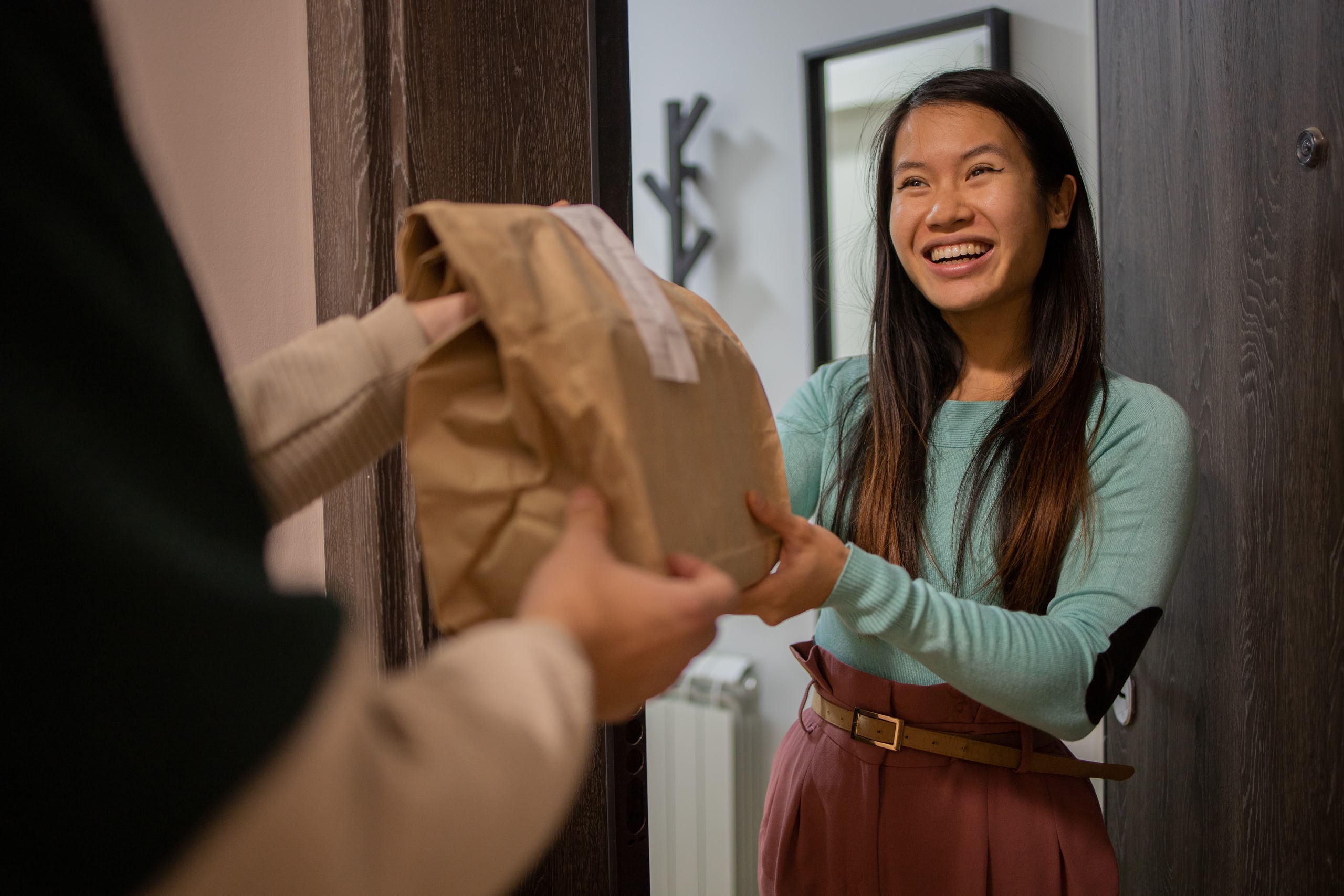 Person receiving a brown paper takeaway bag at the door of their hotel room.