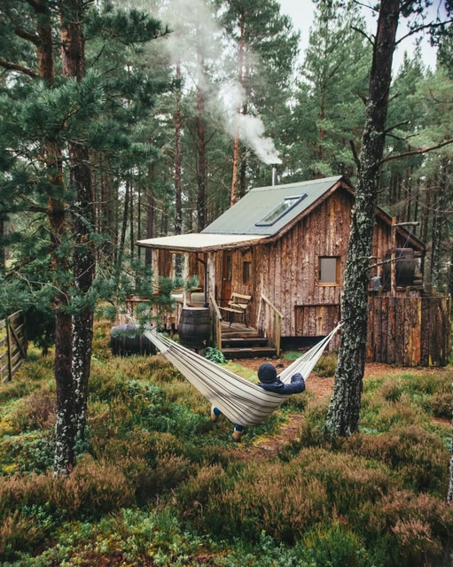 Person relaxing in hammock outside Lazy Duck Cabin, near Aviemore, Cairngorms, Scotland.
