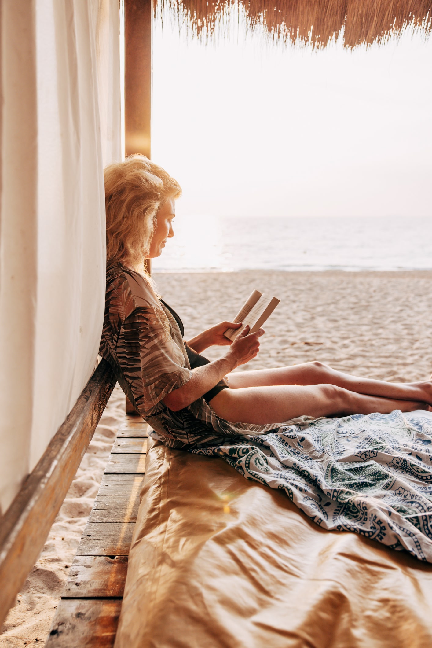 Woman sitting by the beach reading a book on a sunny day.