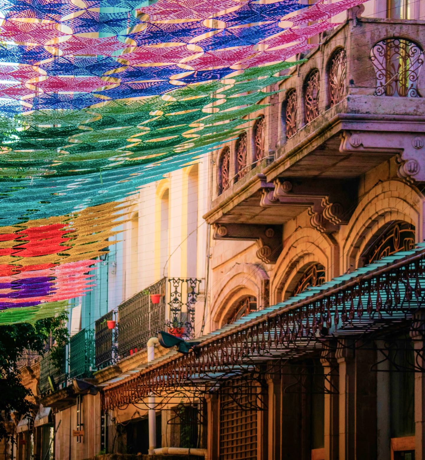 A vibrant knitted canopy stretches from old balconies and buildings in Guadalajara, Mexico.