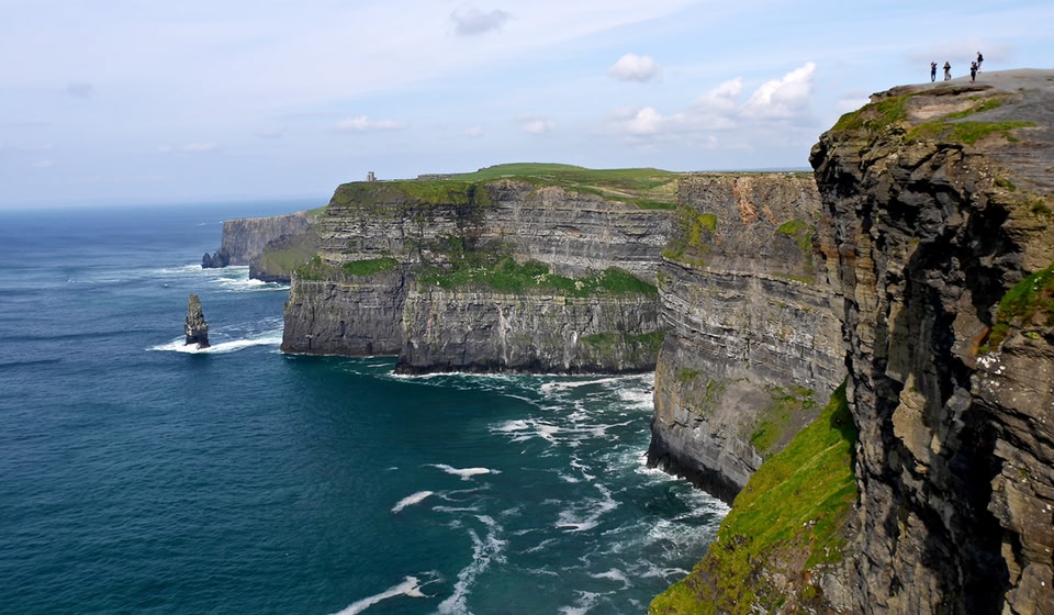 View of people standing atop the Cliffs of Moher