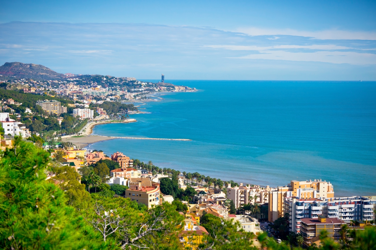 A view of Malaga City in Spain with buildings and a beach.