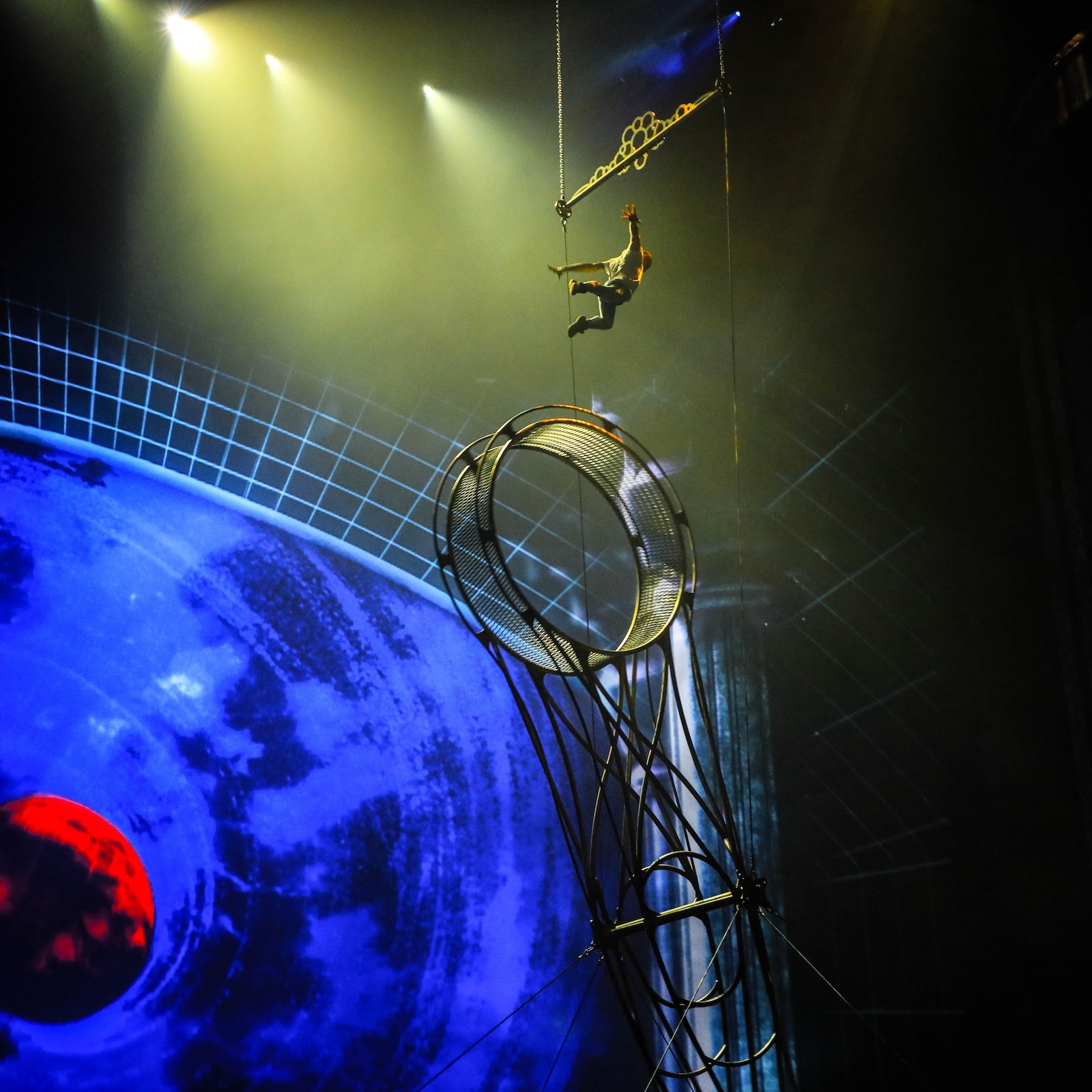 acrobat doing a flip at La Perle by Dragone performance in Dubai, lit up stage and visuals in the background.