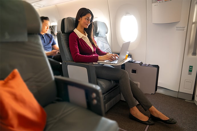 Person sitting in an airplane seat on their laptop