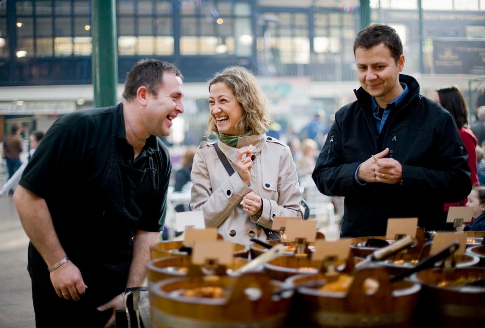 Group of people laughing together while admiring the wares in St George's Market, Belfast
