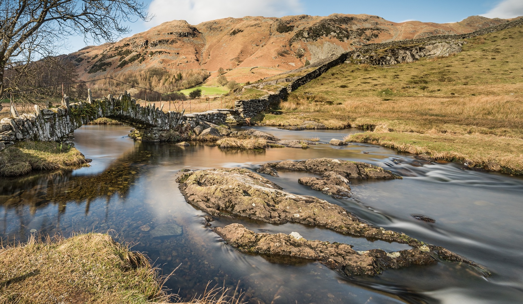 Slater bridge in the Lake District, an old stone bridge spanning a calm river in remote countryside