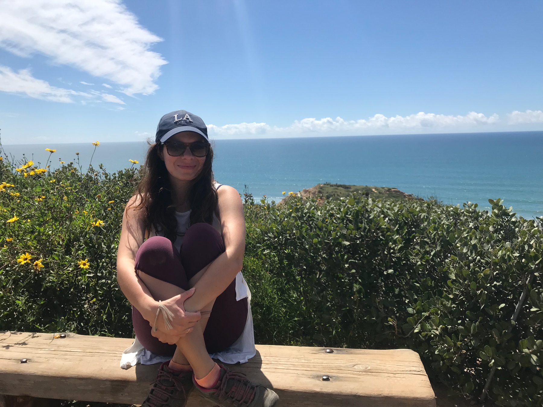solo traveller wearing a hat and sunglasses sitting on a bench at Torrey Pines National Park in San Diego, California