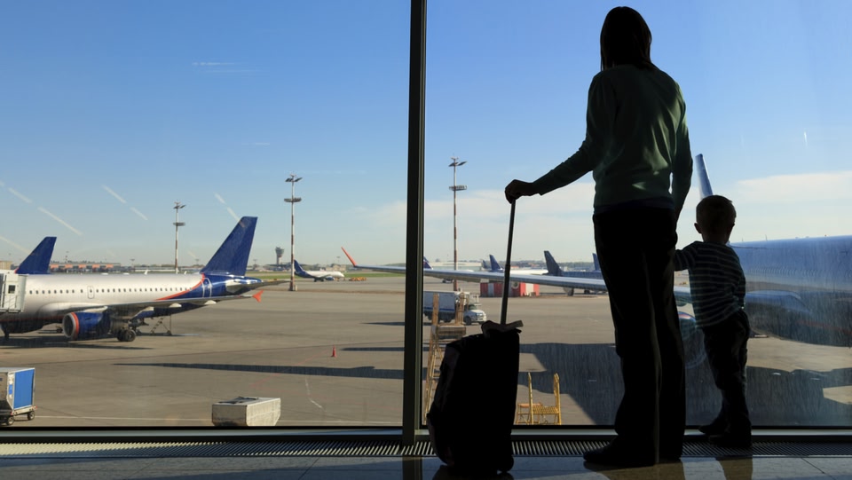 genitore e bambino che guardano gli aerei attraverso una finestra in un aeroporto